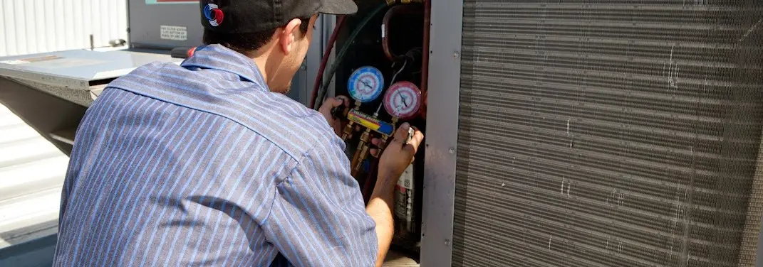 HVAC technician servicing a condenser unit in Freeport